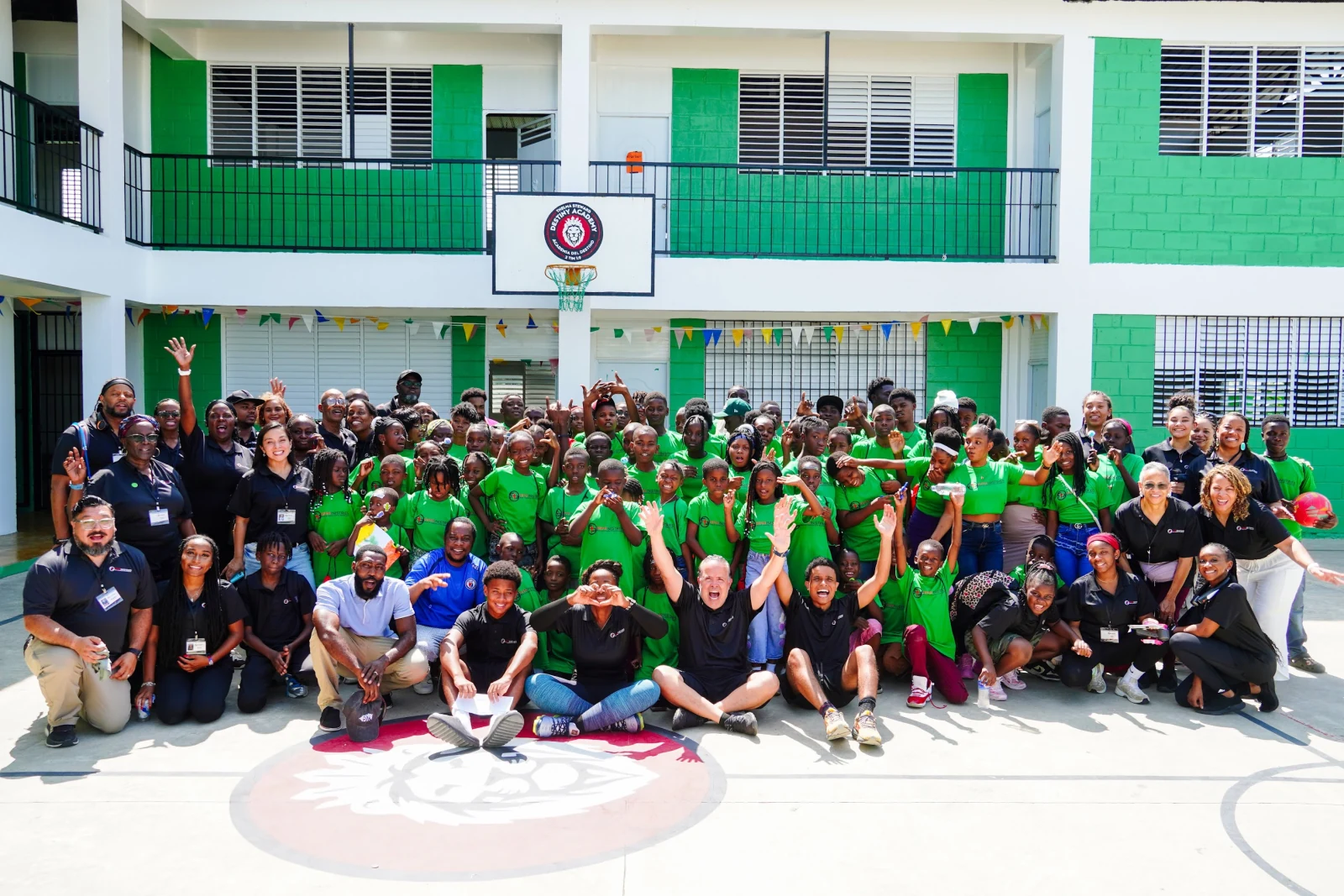 Students and volunteers gathered in the school courtyard at Destiny Academy, with the school building and basketball hoop behind them.